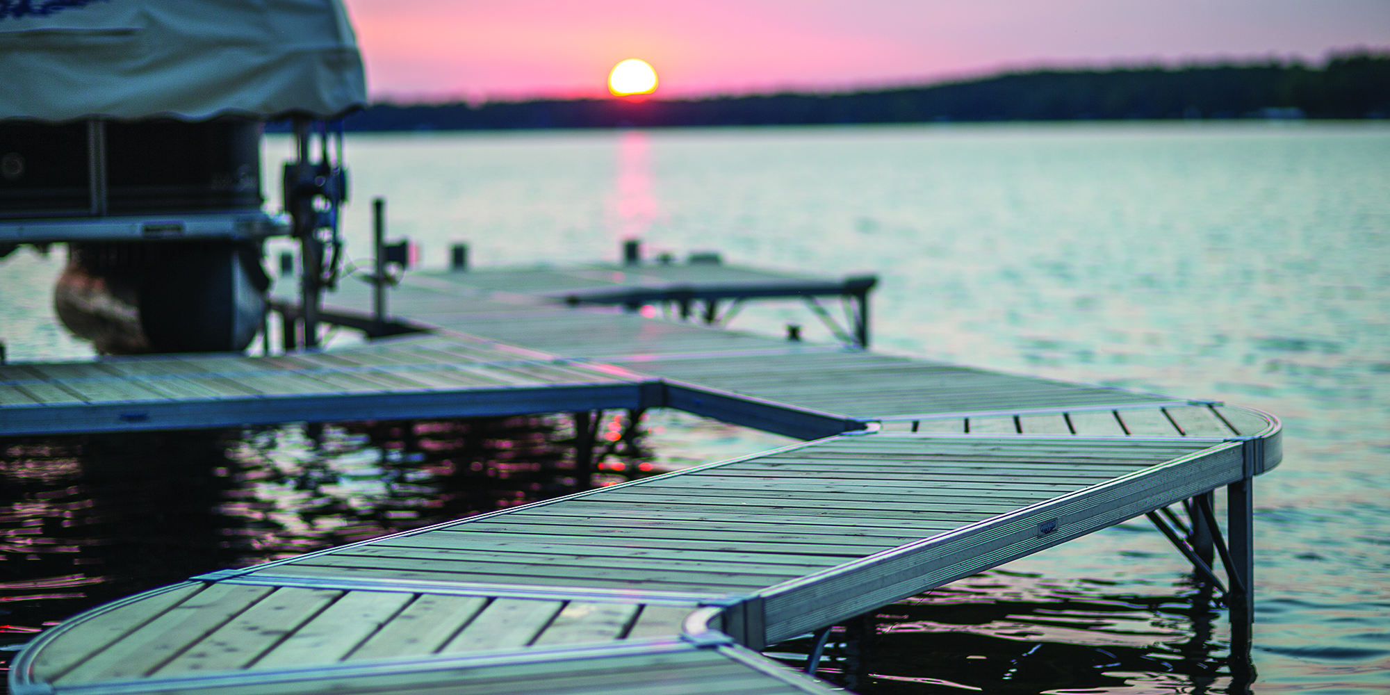 a dock on a lake with a sunset in the background